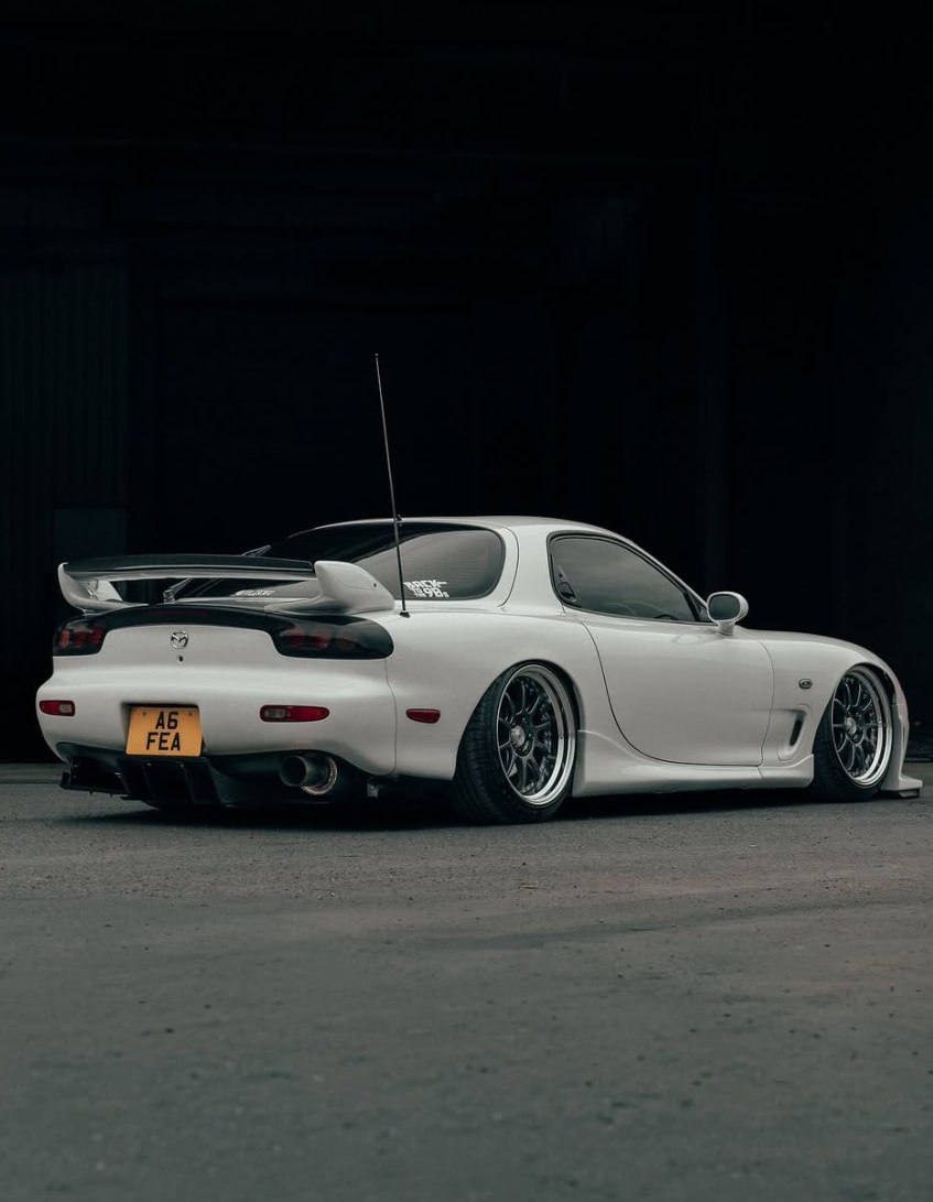 Rear three-quarter view of the RX-7 showing the wing, wheels, and full side profile