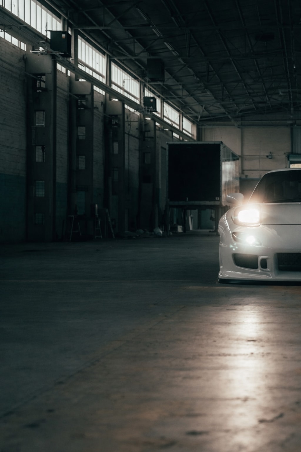 Negative-space front crop of the RX-7 with headlight spill across the floor