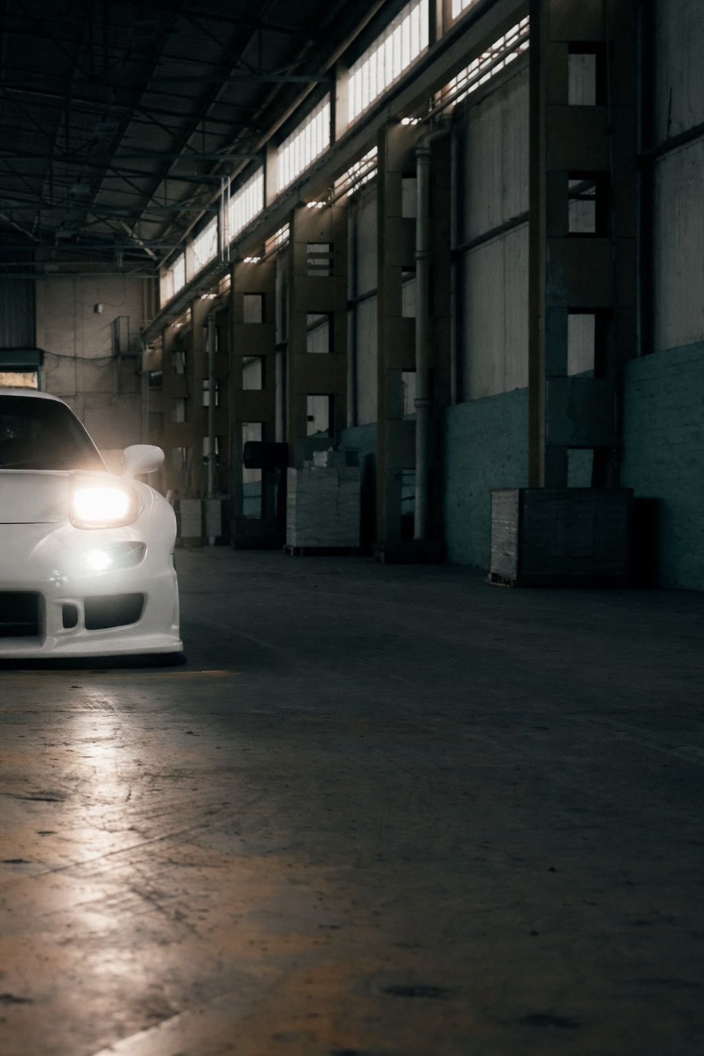 Tighter front crop of the RX-7 showing headlight flare in the warehouse